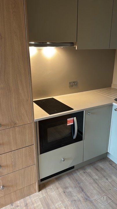 Close view of hob, oven and oak-effect tall column in a fitted kitchen