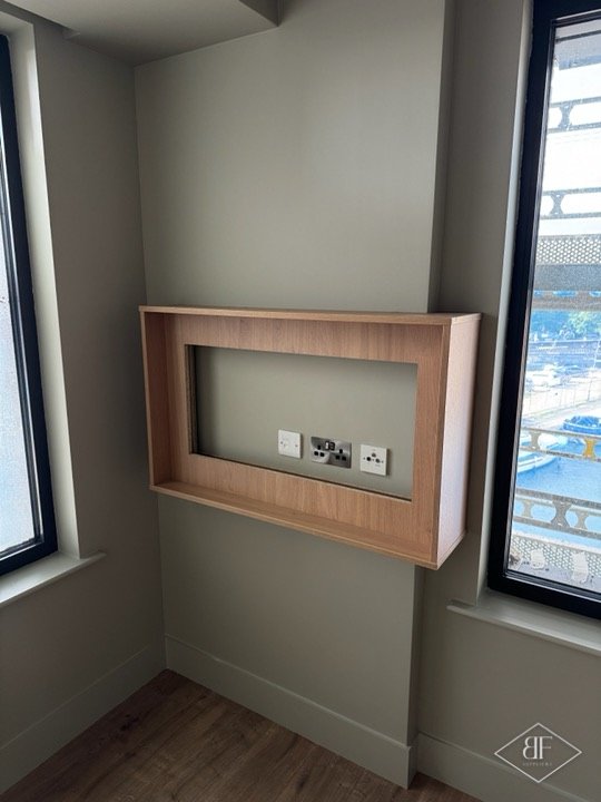 Oak-effect framed recess for a wall-mounted television between two windows