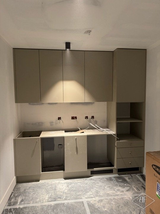 Grey kitchen wall units and base cabinets installed before worktop appliances were fitted