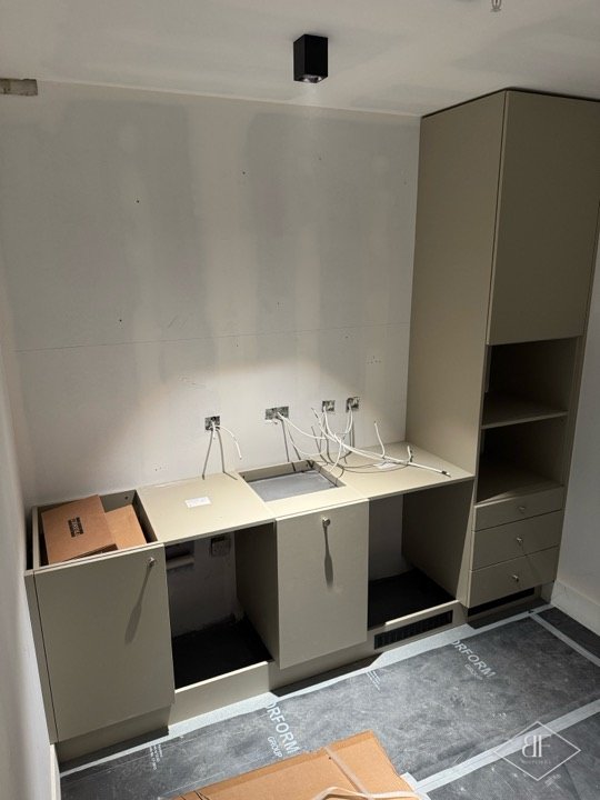 Base units, worktop and tall storage column in place with service cables still exposed