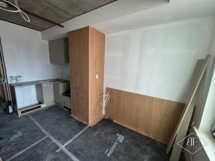 Oak-effect tall unit and wall panelling fitted in a kitchen before worktop completion