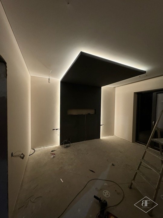 Living room with dark feature wall recess and LED cove lighting in a London apartment