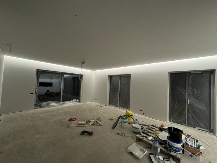 Open apartment living space with continuous LED cove lighting along the ceiling edge