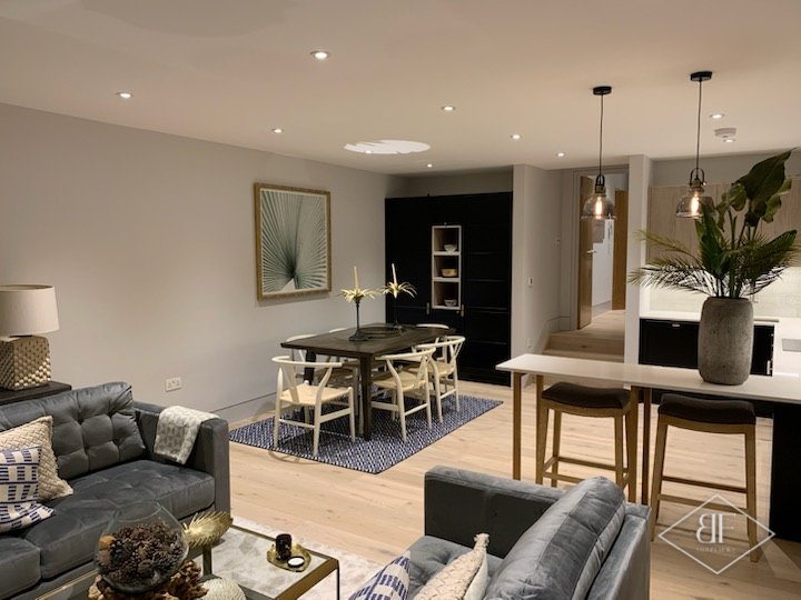 Apartment lounge and dining area with grey sofas and a black wardrobe unit behind