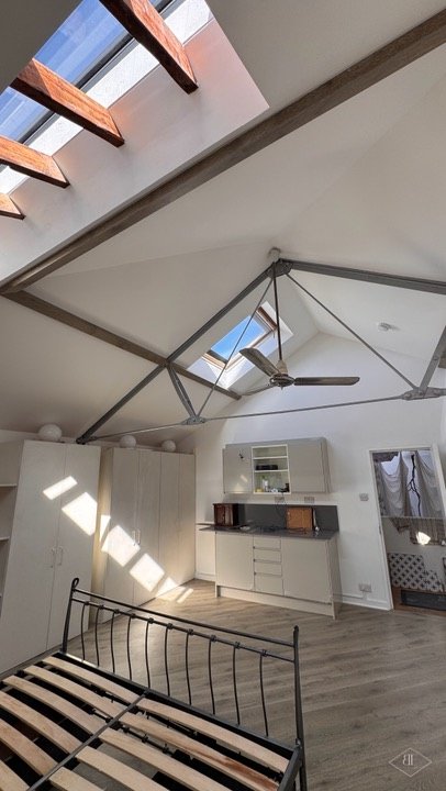 Bright loft room with skylights, built-in units and wardrobes beyond the bed frame