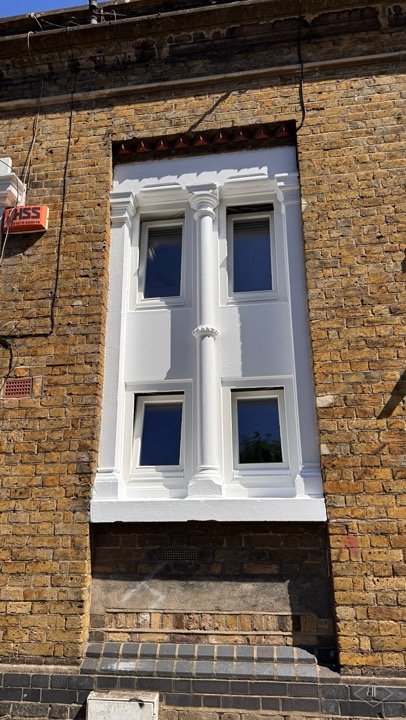 Brick facade with newly installed white framed windows and decorative surround in Archway