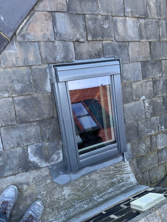 Roof window set into slate with metal flashing, seen from the roof