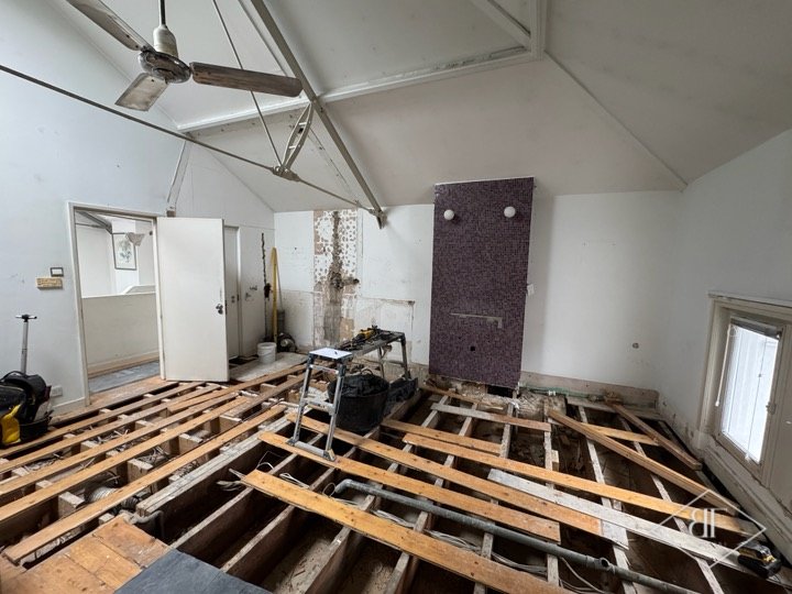 Bedroom floor stripped back to joists, with tiled chimney breast, before renovation