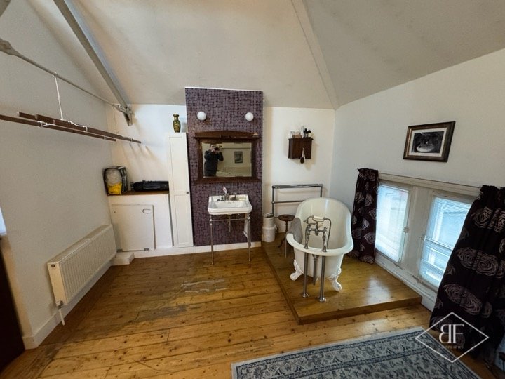Original room before renovation, with timber floor, freestanding bath and tiled chimney breast