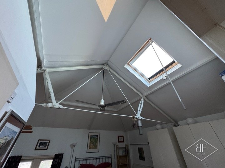 High vaulted loft ceiling with rooflight, tie rods and ceiling fan after decoration