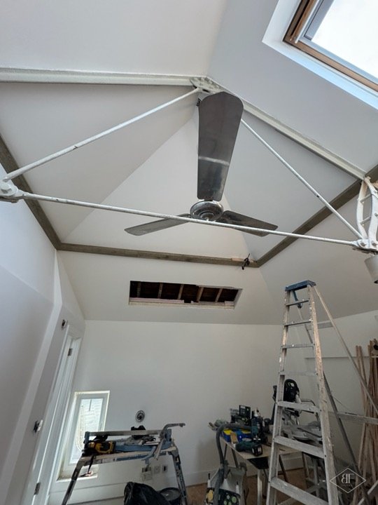 Loft room with new ceiling boards, rooflight and workshop tools below, during works