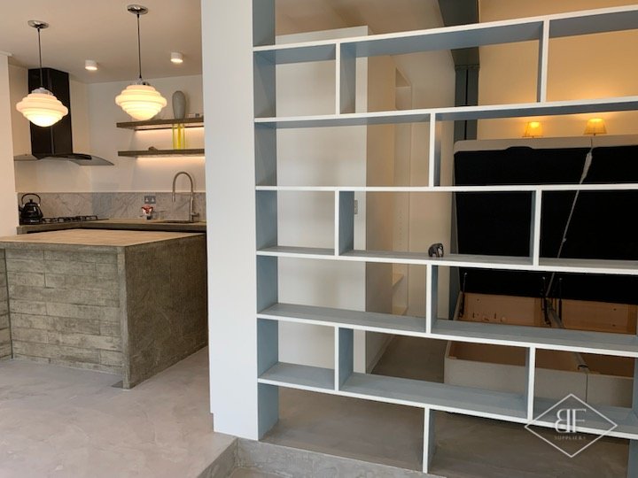 Open blue shelving divider next to the kitchen island with a lit shelf above the worktop