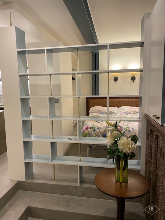 Bespoke shelving divider separating the kitchen from the bed area in the basement studio