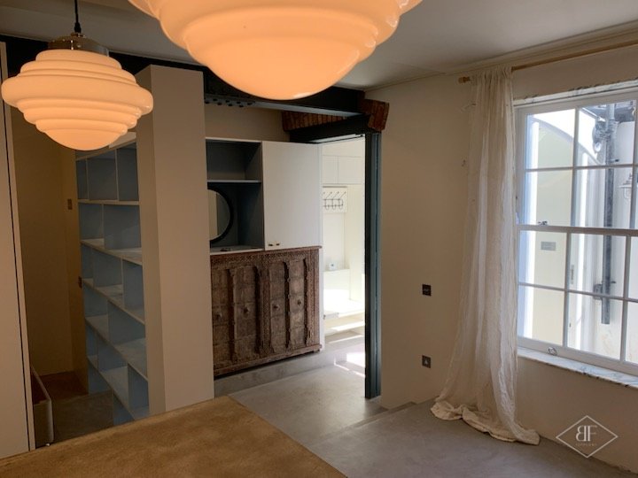 Shelving unit and wardrobe beside the window with an ornate carved cabinet beyond
