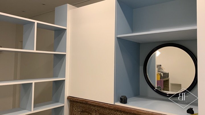 Bespoke white and blue shelving unit with round mirror above carved timber panelling in Kensington