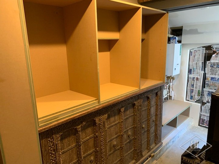 Plywood carcass shelving built above carved timber panels before painting