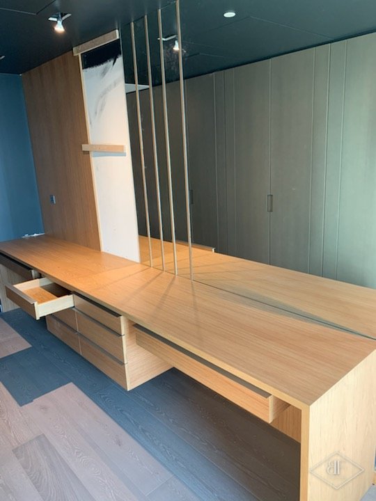 Long oak dressing desk with drawers and mirrored panels beside tall wardrobes