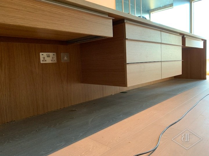 Underside of the oak desk showing a socket, floating drawers and a panelled back