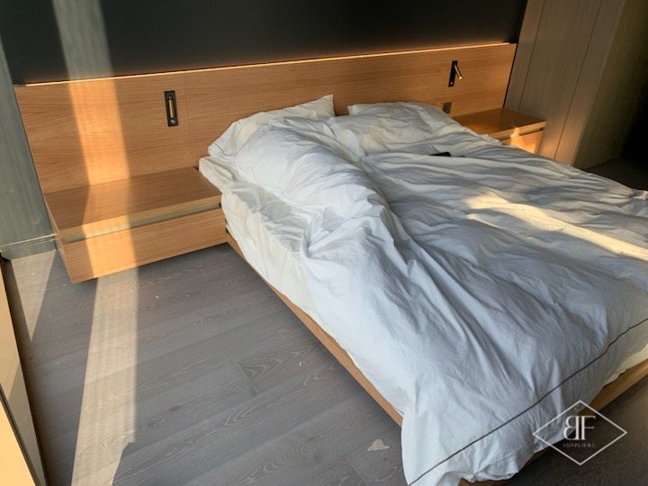 Oak headboard with reading lights above a bed with oak side shelves