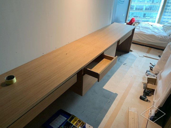 Long oak desk with a drawer pulled out, with the room still being finished