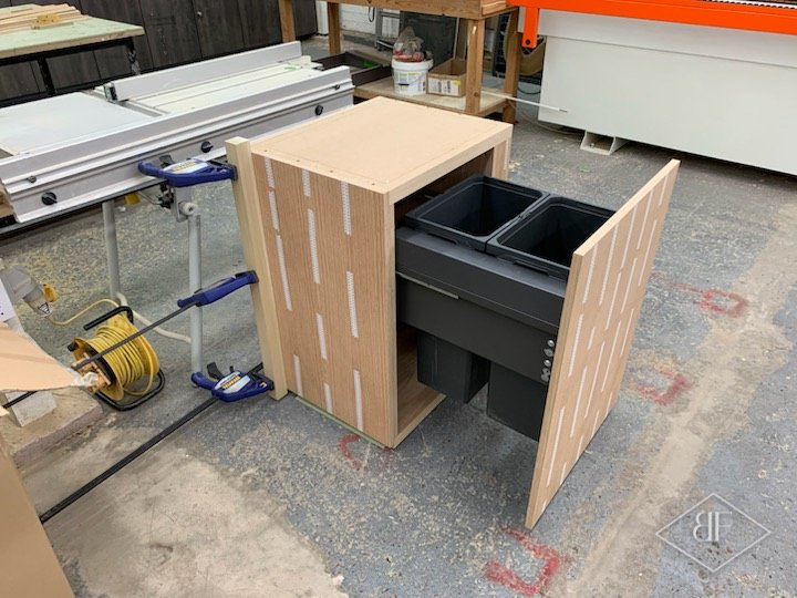 Workshop-built oak slatted cabinet with a pull-out double waste bin before installation