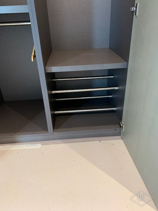 Wardrobe compartment with shelf and pull-out rails in grey finish, doors open