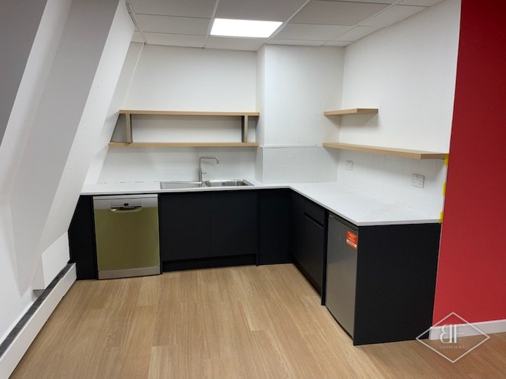 Corner kitchen area with dark cabinets, integrated appliances and a red feature wall