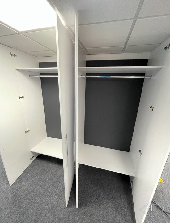 Empty white wardrobe carcass with hanging rails and shelves during installation