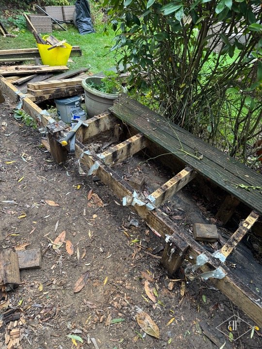 Exposed timber joists and metal brackets after old garden decking was removed