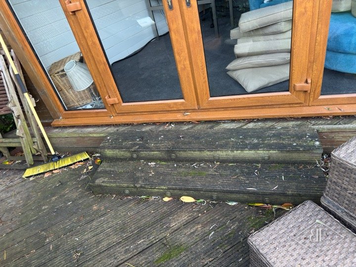 Worn timber decking and steps outside a garden room before replacement