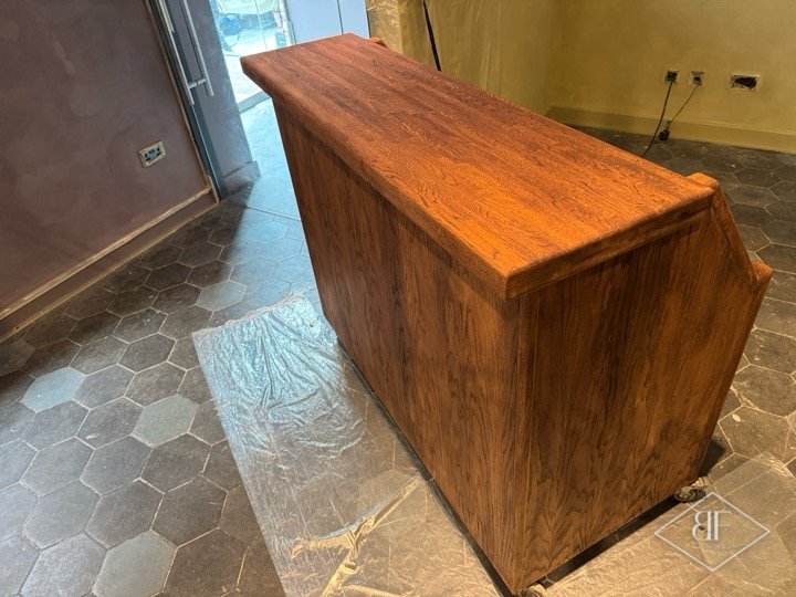 Three-quarter view of the stained timber booth on a hexagon-tiled floor