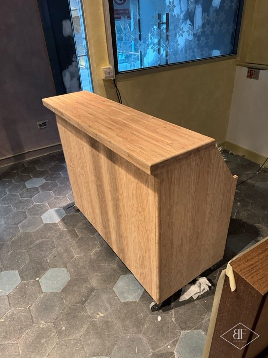 Light unstained timber booth in progress on hexagon floor tiles before staining