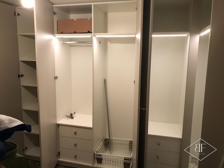 Lit wardrobe interior with shelves, drawers and a wire basket