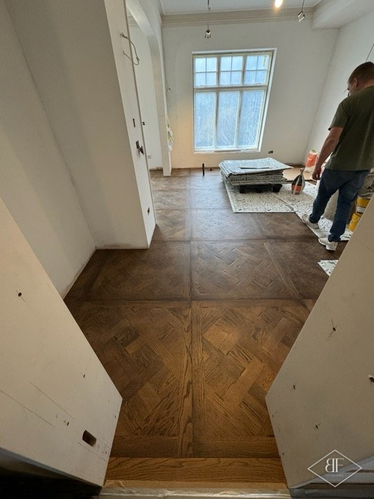 Herringbone parquet panels in a doorway leading to a bright room with leaded windows