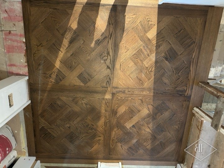 Close view of dark parquet floor panels with a herringbone pattern