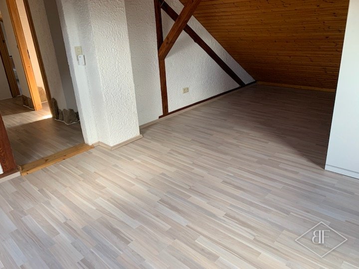 Light laminate flooring in an attic room with exposed timber beams