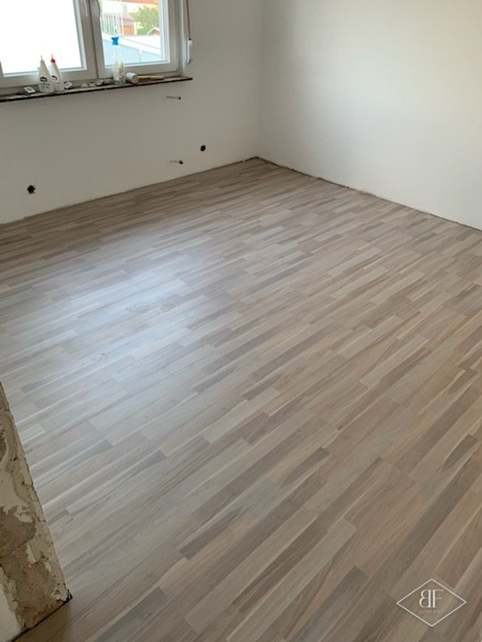 Newly laid light plank floor in an empty room with white walls