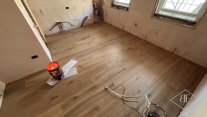 Fresh timber floor in a room being renovated, with exposed pipework on the walls
