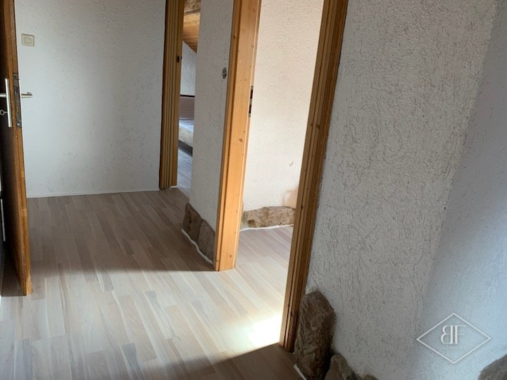 Hallway with finished pale wood-effect flooring leading to a doorway