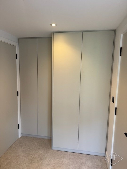 Two sets of tall, plain-faced wardrobe doors fitted in a bedroom recess