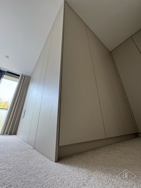 Sloping handleless wardrobe doors cut to the roof angle in a London bedroom
