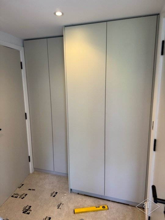 Tall handleless wardrobe doors fitted beside a doorway, shown during the final stage