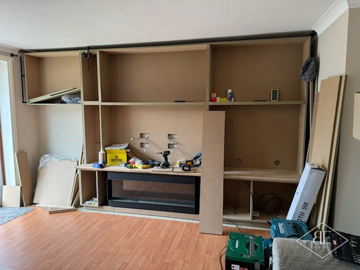 Early stage media wall framework with a fire unit in place and tools nearby