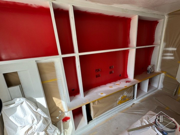 Shelving frame primed white with red painted recesses and protective sheeting in Walthamstow