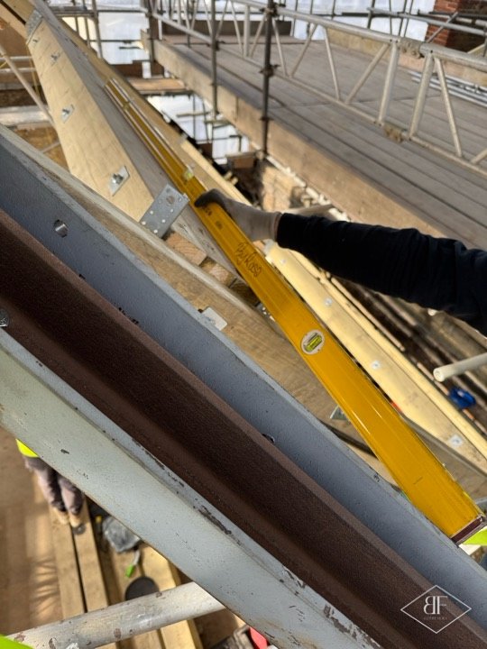 Checking a new timber roof rafter with a spirit level beside a steel beam