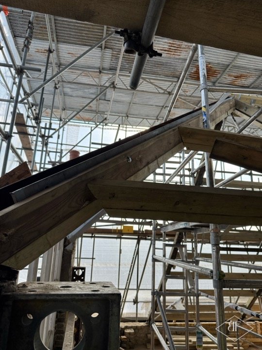 Central steel ridge section meeting new timber members in the roof structure