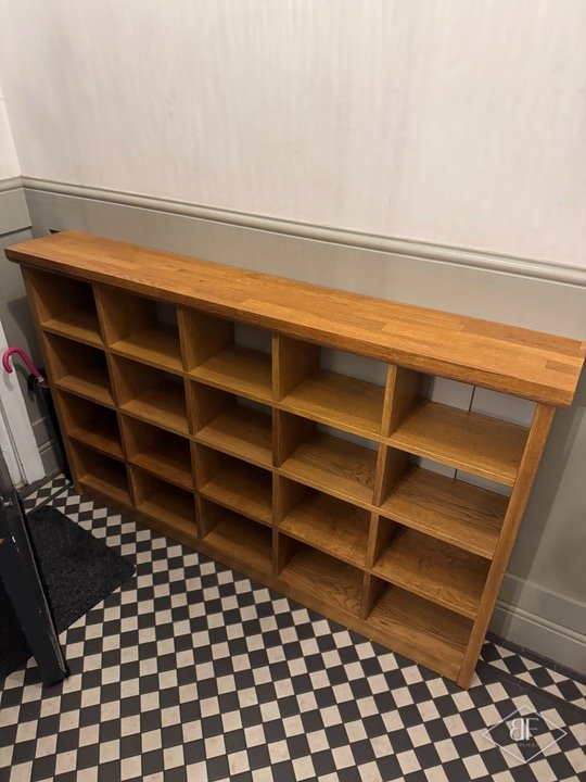 Finished oak shoe rack unit against a hallway wall above a chequered tile floor