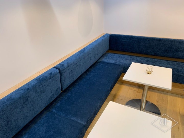 Close view of the deep blue banquette seating and square white table