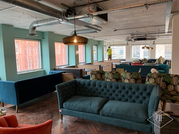 Large office breakout floor with teal sofas, herringbone flooring and exposed ducting