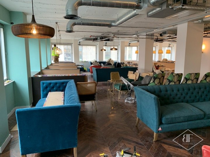 Lounge seating area with teal sofas and booth seating beyond during fit-out